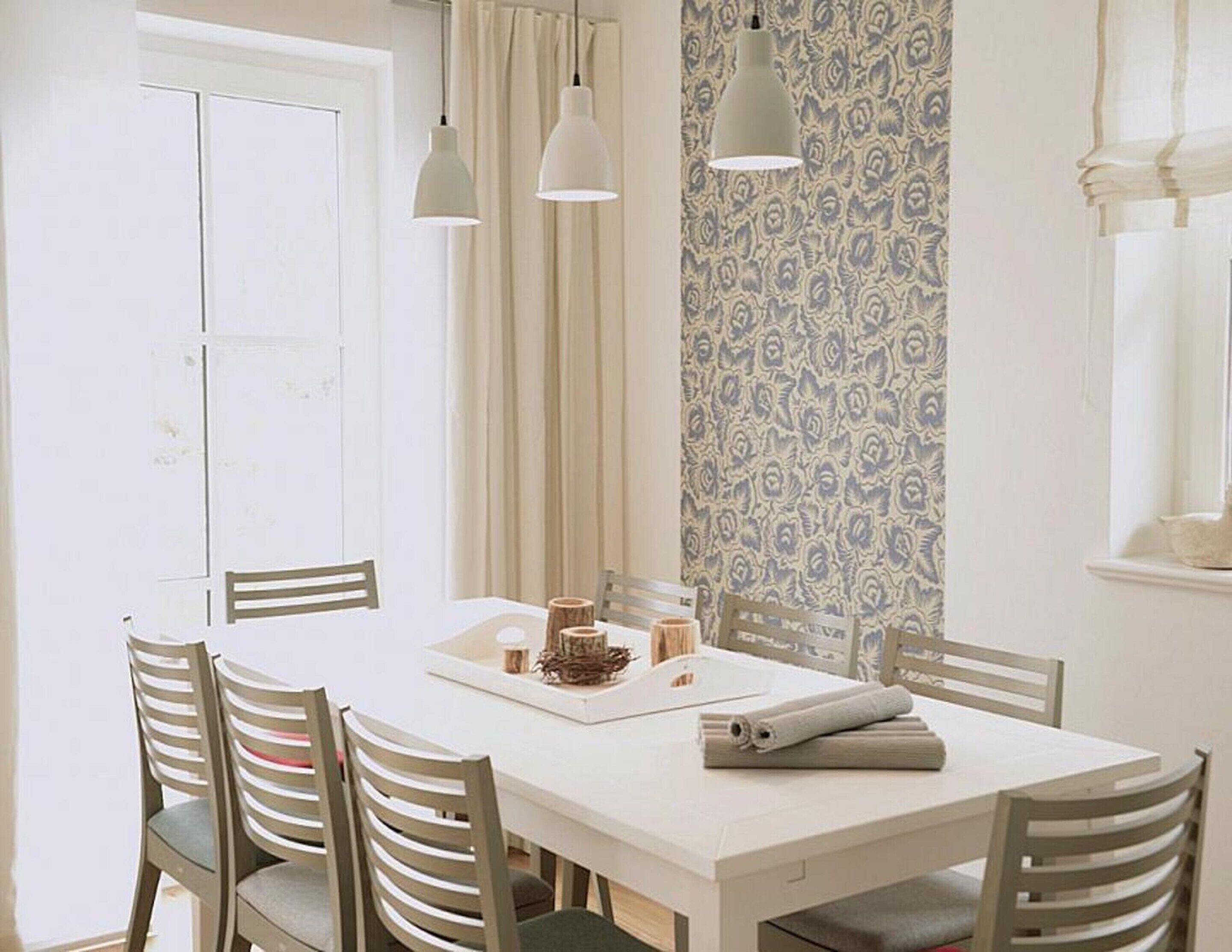 A dining area with a white table, six chairs, and pendant lights.