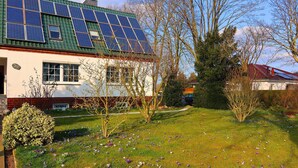 Una casa con paneles solares en el techo, un jardín lleno de flores y un cielo despejado.