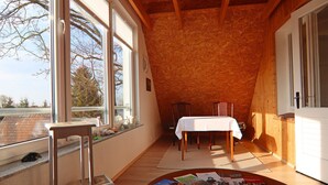 Una habitación acogedora con techo de madera, una mesa de comedor con mantel blanco y una ventana con vistas a árboles.