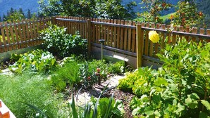 Un giardino con recinzione in legno, diverse piante e un piccolo elemento decorativo a base d'acqua.