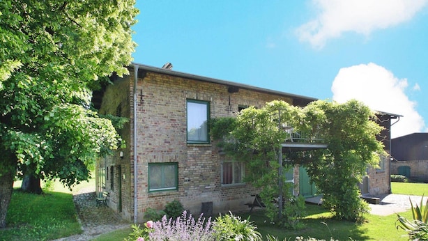 A two-story brick building with a garden in front, including a pathway and various plants. - Ferienhaus, Zahrensdorf (Kloster Tempzin)