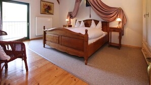 A wooden bed with a canopy, a nightstand, a chair, and a painting on the wall. - Ferienhaus, Zahrensdorf (Kloster Tempzin)