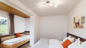A bedroom with a large bed, a smaller bed, and a window with curtains. - Adults Only Apartment With Pool (Sankt Kanzian am Klopeiner See)