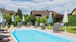 A rectangular swimming pool with clear blue water, surrounded by lounge chairs and umbrellas. - Adults Only Apartment With Pool (Sankt Kanzian am Klopeiner See)