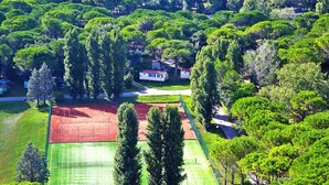 A residential area with houses surrounded by dense greenery, a tennis court, and a well-maintained lawn. - Bungalow in the Residence Belvedere in Grado (Aquileia)