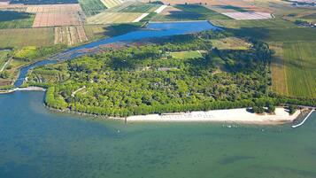 Vista aérea de una zona costera con playa de arena, un río y campos agrícolas circundantes.