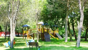 A playground with slides and climbing structures surrounded by trees. - Bungalow in the Residence Belvedere in Grado (Aquileia)