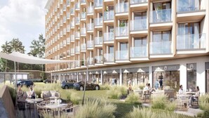 Een modern hotel met meerdere balkons, buitenzitplekken en een café.