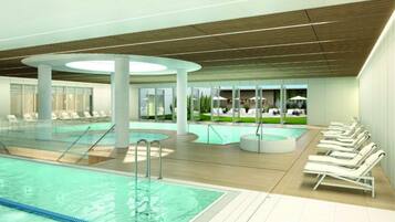 A swimming pool area with multiple pools, sun loungers, and a view of the outdoors.