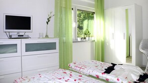 A bedroom with a bed, a dresser, a TV, and a window with curtains. - Ferienwohnung, Tambach-dietharz (Tambach-Dietharz)