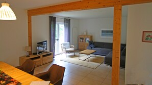 A living room with a wooden ceiling, a television, a sofa, and a dining area with chairs. - Ferienhaus Barbara, Zarrentin (Zarrentin am Schaalsee)