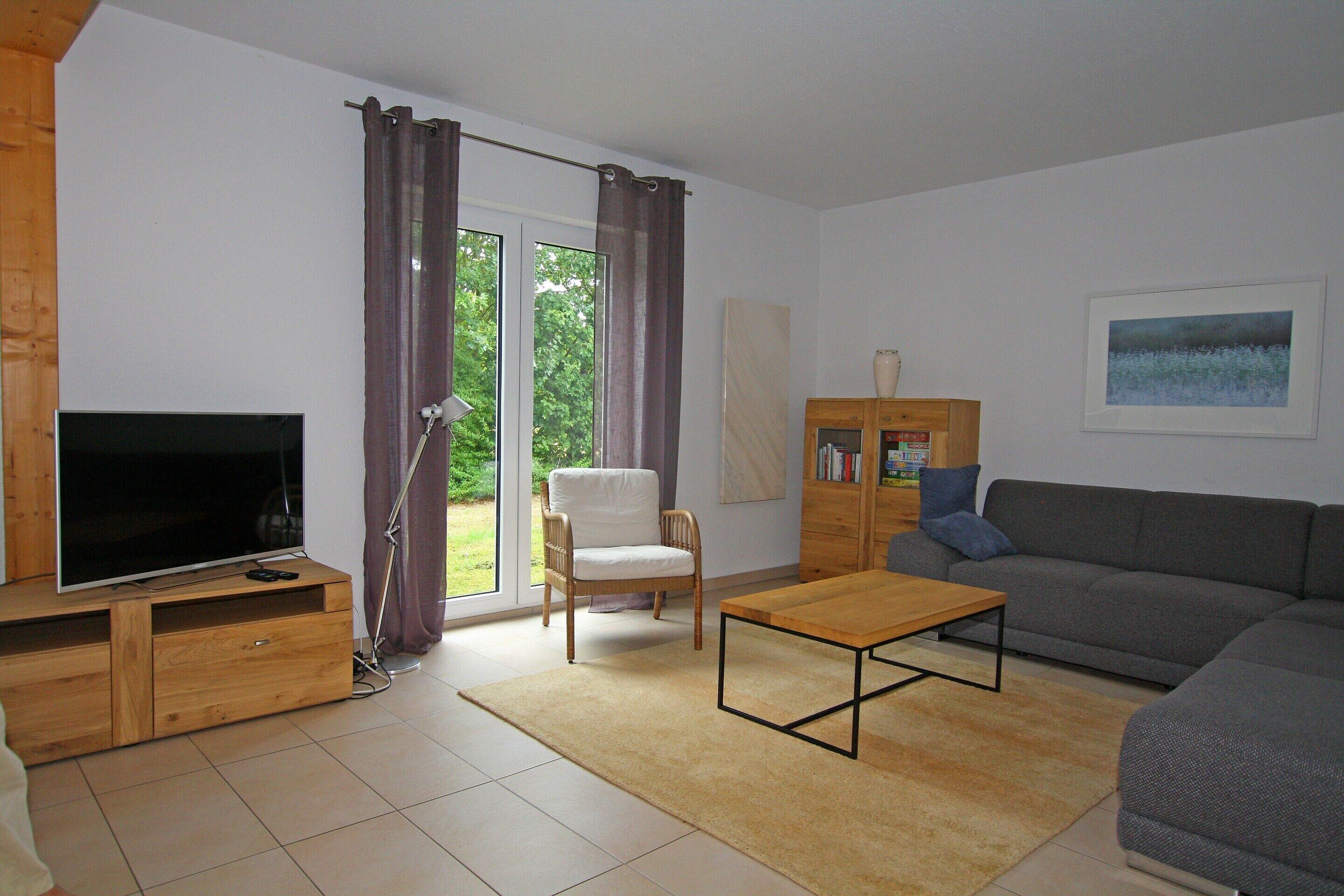 Een woonkamer met een televisie, bank, salontafel en stoel.