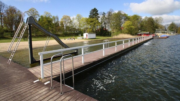 A wooden dock extending over water with metal railings and a ladder. - Ferienhaus Barbara, Zarrentin (Zarrentin am Schaalsee)