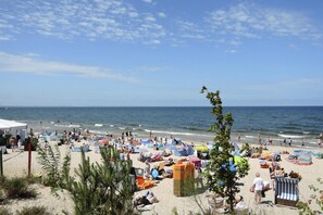 Une plage avec de nombreux transats, des parasols et beaucoup de baigneurs.