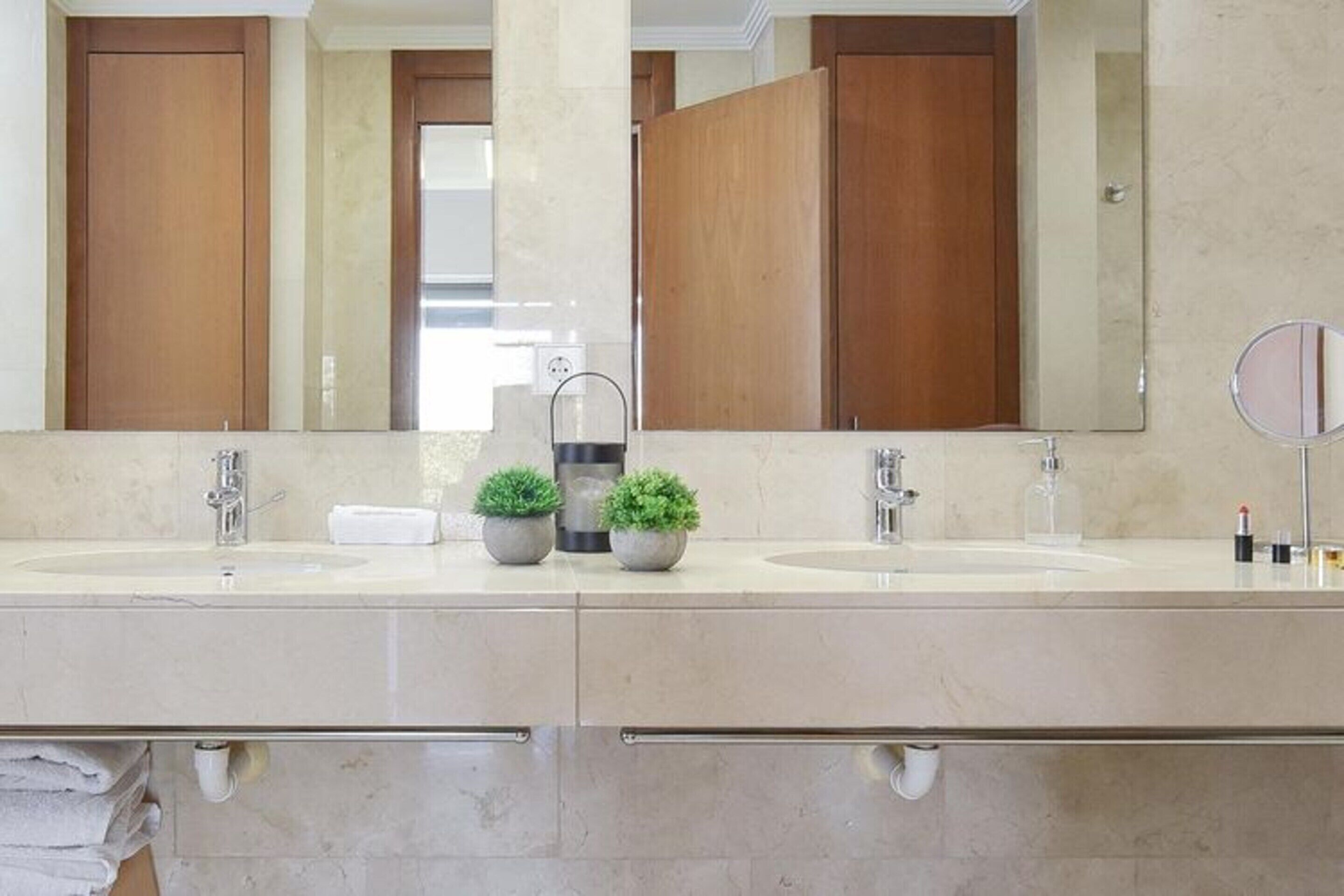 A modern bathroom with two sinks, a large mirror, and wooden cabinets.