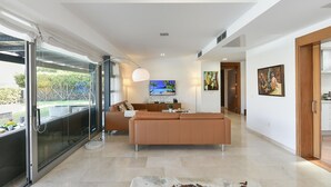A modern living room with a sofa, TV, and artwork. - Villa With Private Pool in the Golf Resort (San Bartolomé de Tirajana)