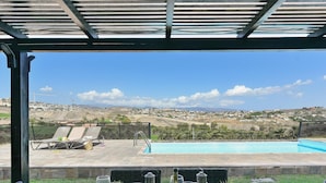 An outdoor dining area with a view of a swimming pool and distant landscape. - Villa With Private Pool in the Golf Resort (San Bartolomé de Tirajana)