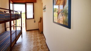 A room with bunk beds, a window with curtains, a painting on the wall, and a tiled floor.