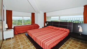 A hotel room with two beds, a large window with a view, a bedside table with a lamp, and a nightstand.