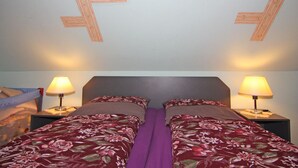 Ein Schlafzimmer mit zwei Betten, einem Deckenfresko mit einer tropischen Strandansicht und zwei Nachttischlampen.