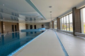 A spacious indoor swimming pool with a marble wall and a reception desk. - Apartment Overlooking the River, Sauna, Dziwnow (Dziwnów)