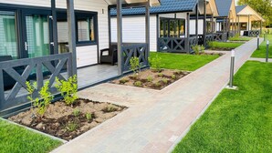 A row of modern, single-story buildings with covered porches and a well-maintained lawn. - Summer House in Jaroslawiec Near Beach & Pool (Postomino)