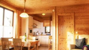 A wooden cabin interior with a dining area, kitchen, and a cozy sitting area. - Doppelhaushalfte in Hasselfelde (Oberharz am Brocken)