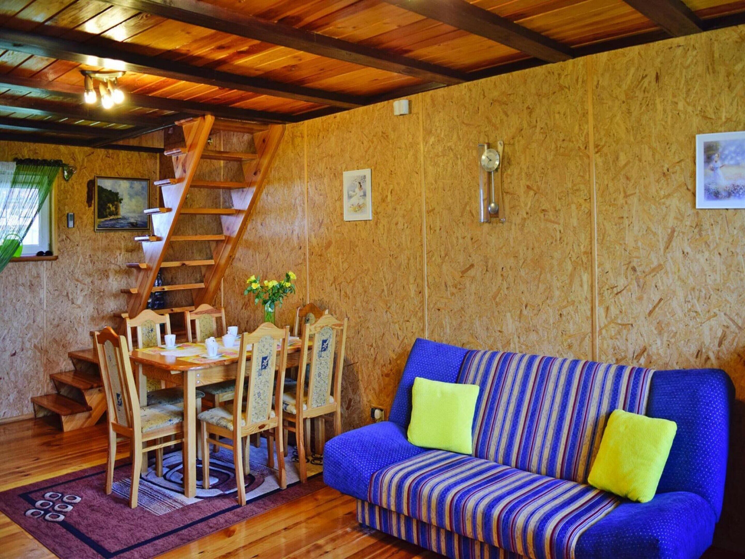 A cozy room with a wooden staircase, a dining table with chairs, and a striped sofa with cushions.