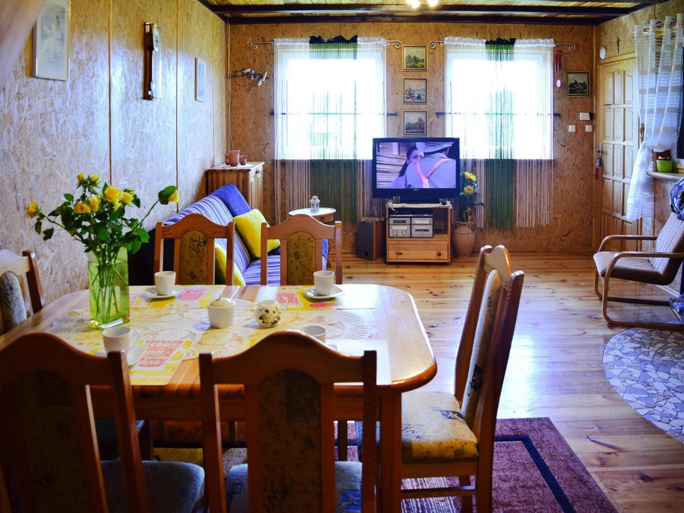 Un accogliente soggiorno con un tavolo da pranzo in legno, sedie, un divano e una televisione.