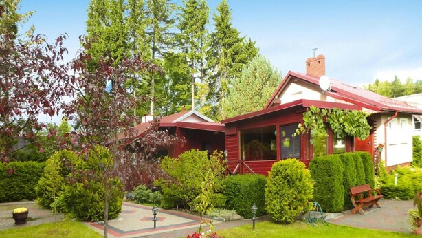 Une maison en bois rouge avec un jardin devant.
