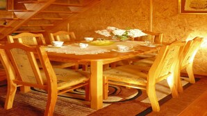 Une table à manger en bois, avec des chaises, une nappe en dentelle et un vase rempli de fleurs.