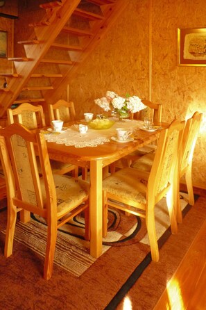 A wooden dining table with chairs, lace tablecloth, and a vase of flowers. - House Near Lake Zawiat and Baltic Sea (Wejherowo)
