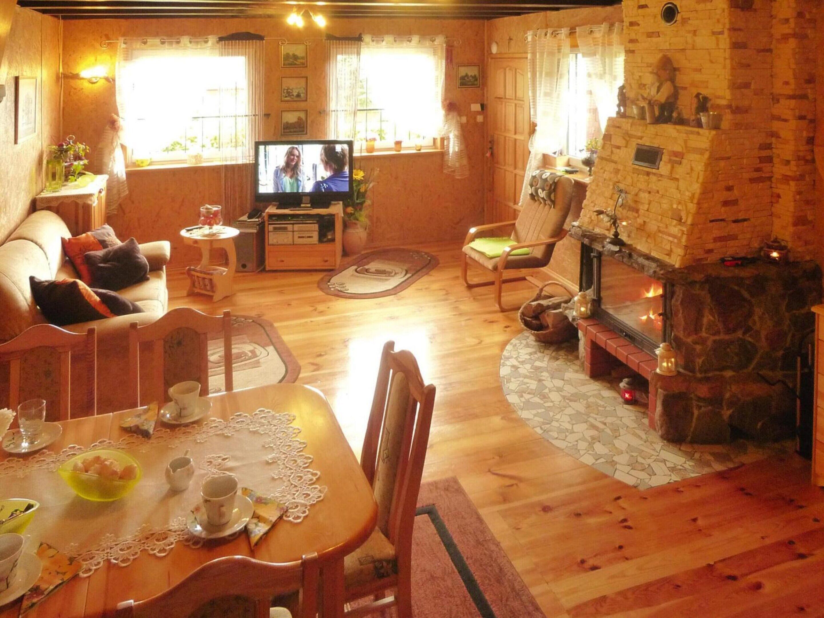 A cozy living room with a fireplace, wooden furniture, and a television.