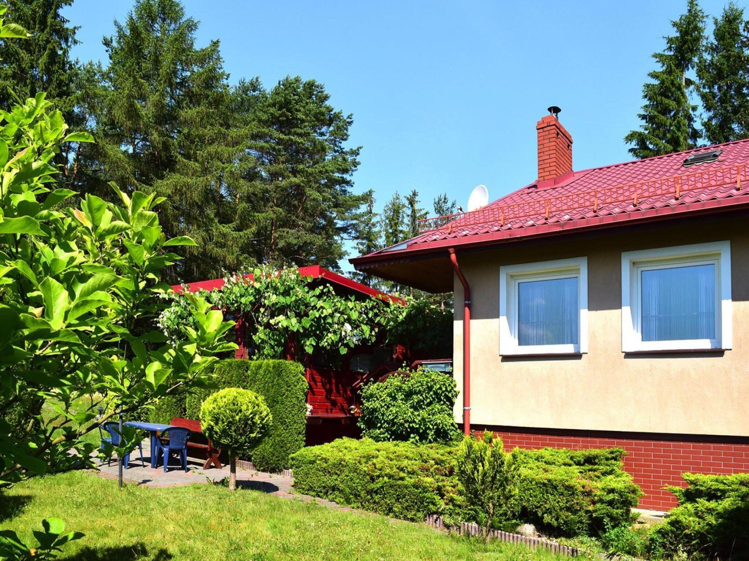 A house with a red roof, two windows, and a brick wall.