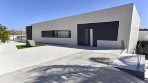 A modern building with a flat roof, large windows, and a paved courtyard.