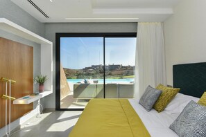 A modern hotel room with a large bed, a view of a pool and hills, and a sliding door to a balcony. - Holiday Home, Maspalomas (San Bartolomé de Tirajana)