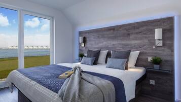 A modern bedroom with a large bed, a view of the sea, and a wooden headboard.