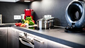 Una cocina moderna con electrodomésticos de acero inoxidable, una encimera negra y una cafetera roja.