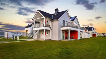 A modern two-story house with a balcony, a covered porch, and a garage.