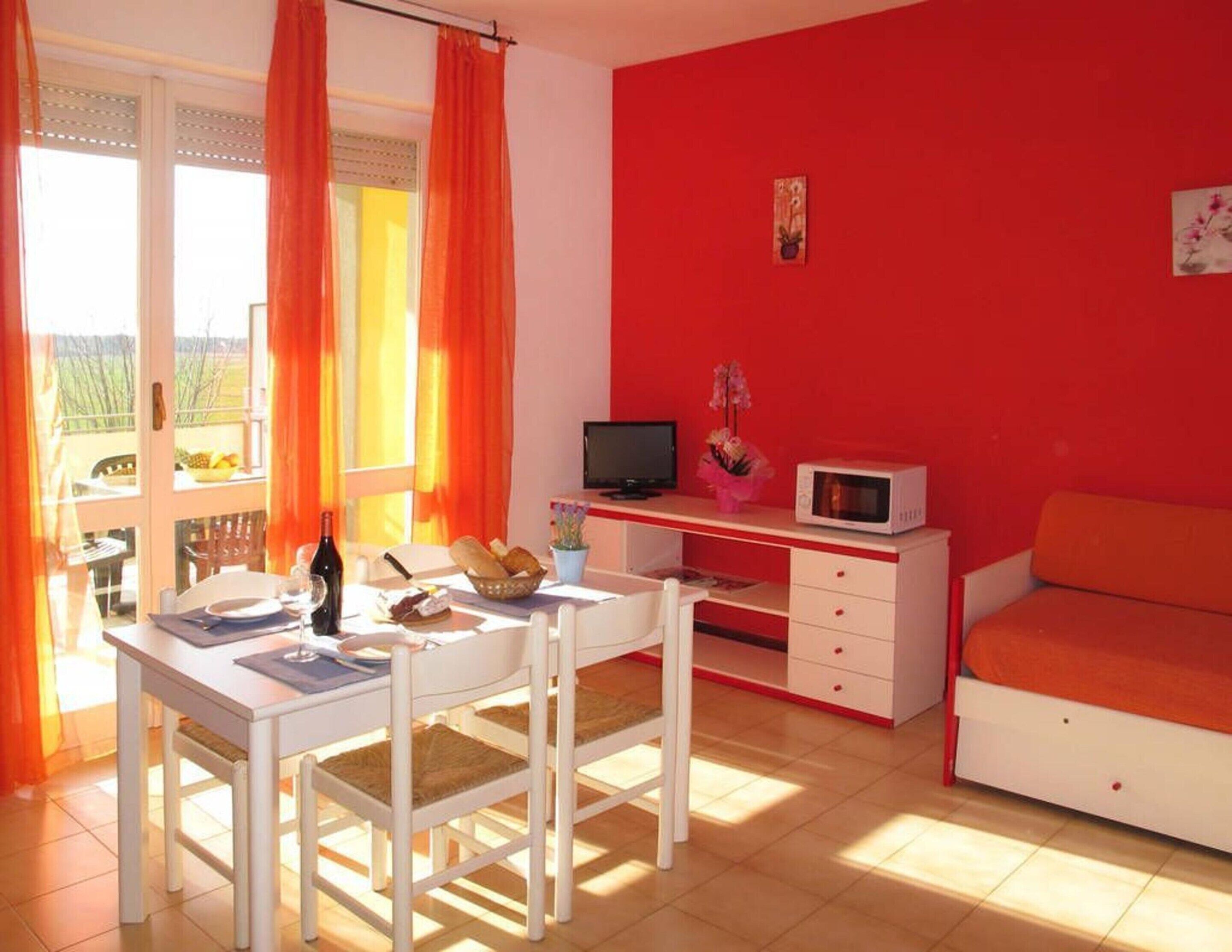 Ein Zimmer mit Esstisch, Stühlen, Fernseher, Mikrowelle und einer Couch.