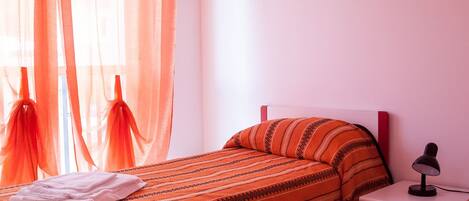 A bedroom with a bed, a nightstand, and a lamp.