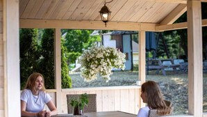 A wooden outdoor seating area with a hanging flower arrangement, a table, and a bench. - Bungalow in Miedzyzdroje Near Baltic Beach (Miedzyzdroje)
