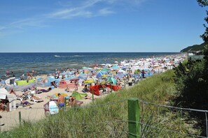 Uma praia movimentada com vários guarda-sóis e banhistas.