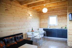 Una cabaña de madera compacta con comedor, kitchenette y sofá con cojines estampados.