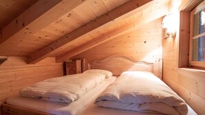 A wooden cabin bedroom with two single beds, a wooden headboard, and a window with a view. - Chalet in Austria Near Ski Lift & Forest (Wald im Pinzgau)