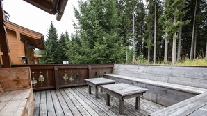A wooden deck with benches and tables, surrounded by tall trees. - Chalet in Austria Near Ski Lift & Forest (Wald im Pinzgau)