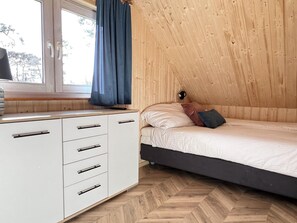 A bedroom with a wooden sloped ceiling, a bed with pillows, a nightstand, and a window with curtains. - Cottage in Pobierowo for 8 People (Rewal)