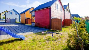 Un hilera de casas coloridas con techo azul, un espacio verde y un parque infantil.