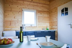 A wooden cabin interior with a dining table set for two, a bottle of olive oil, and apples on the table. - Holiday House in Rewal Near Baltic Beach (Rewal)