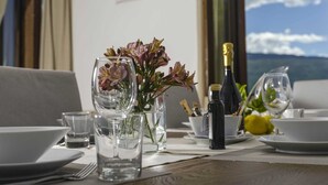 A dining table set with plates, glasses, and a bottle of champagne, with a vase of flowers and a view of the sky. - Il Limone Lake View at Nautic Resort San Carlo (Gargnano)
